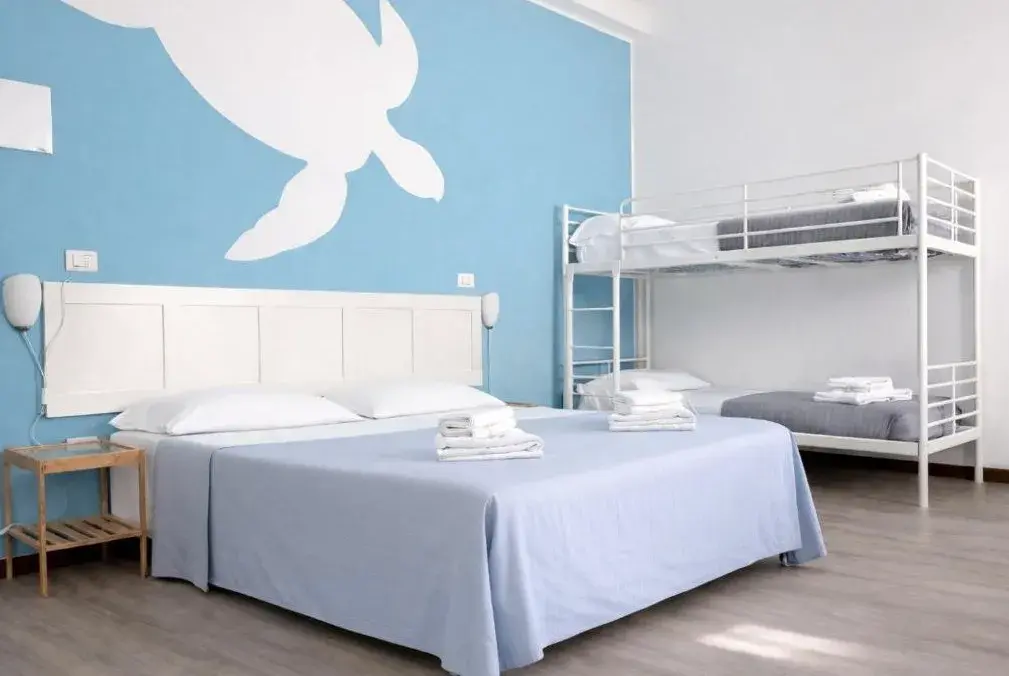 Camera quadrupla con letto matrimoniale, letto a castello e parete azzurra